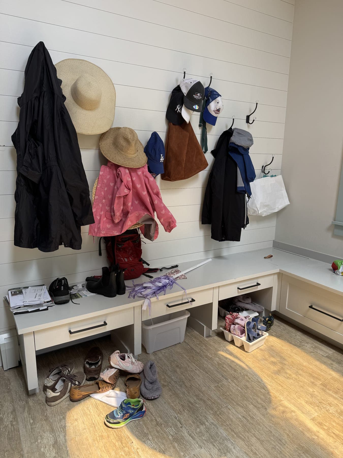 Mudroom bench and hooks overloaded with coats and shoes before organization